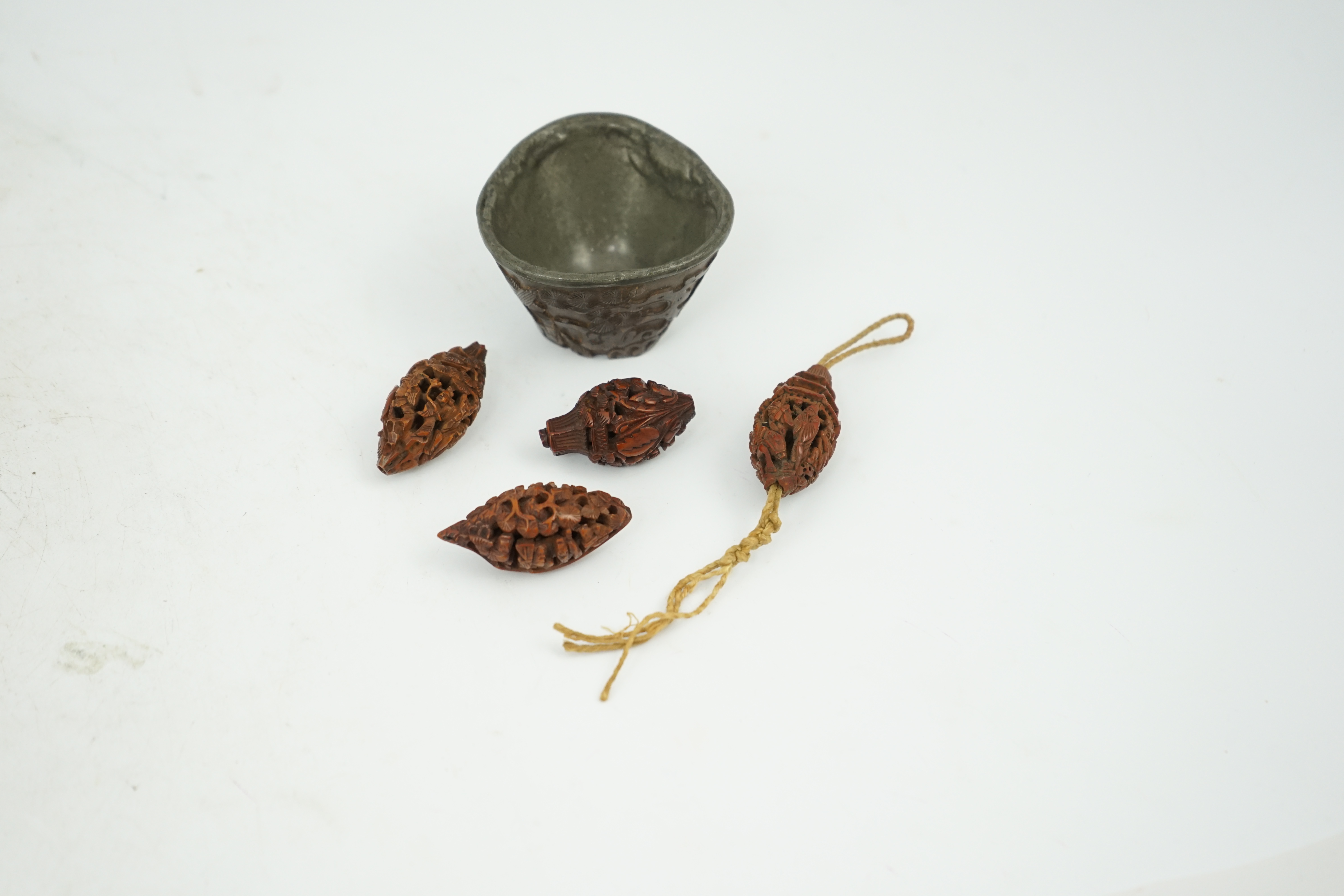 Four Chinese carved peach stones and an 18th/19th century Chinese carved wood cup, 6cm wide (5). Condition - fair to good